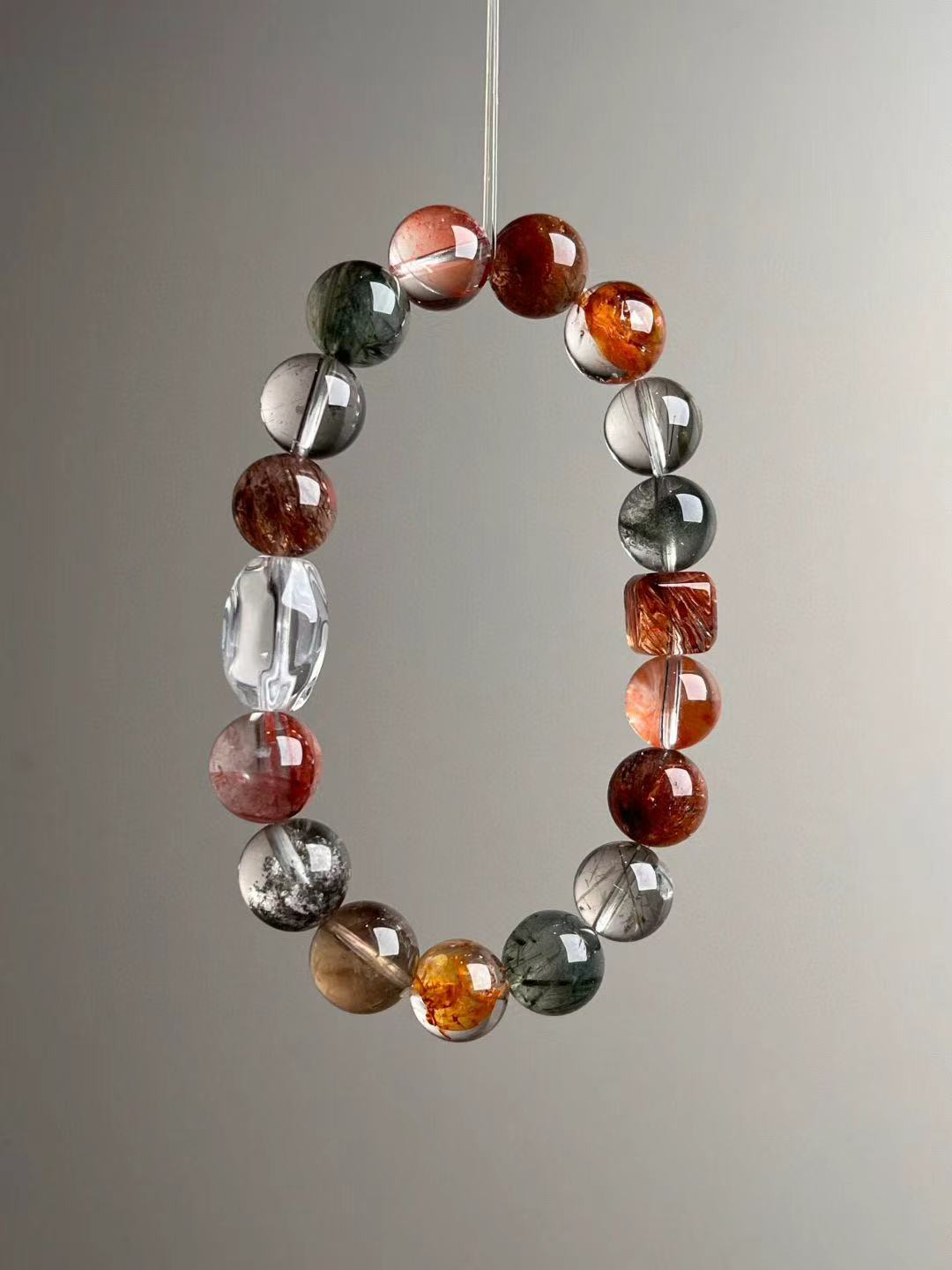 Angle view highlighting the eight-stone matrix—green phantom, red lepidocrocite, green rutilated, clear quartz, ghost inclusions and black-gold super seven.