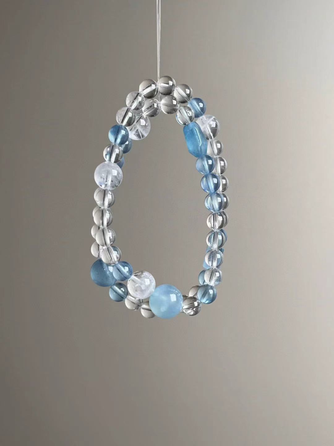 Flat lay — component callouts: aquamarine, clear quartz, white phantom quartz; elastic multi-wrap.