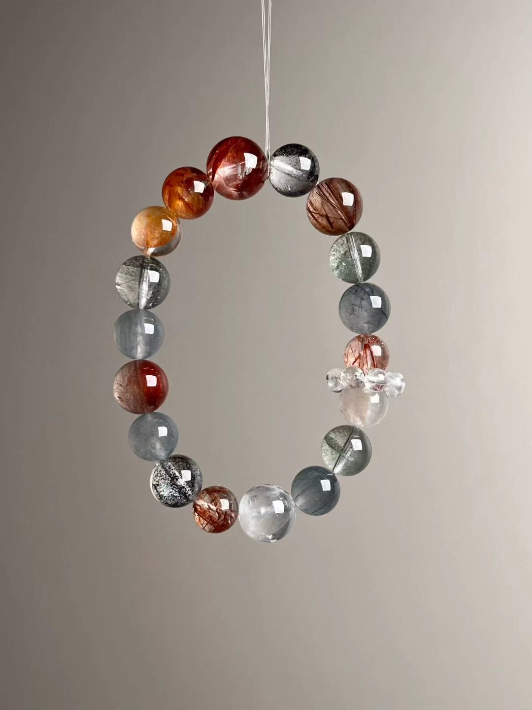Angle view — Black Super Seven with Copper Rutilated Quartz, Yellow Koi Flower Quartz and Green Phantom; clear quartz charm cluster visible.