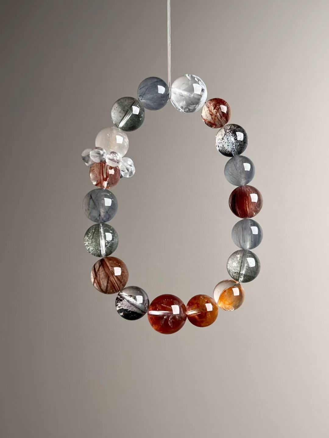 Side angle — gradient of grey-blue rutilated quartz and phantom quartz with faceted beads; protective Super Seven focal.