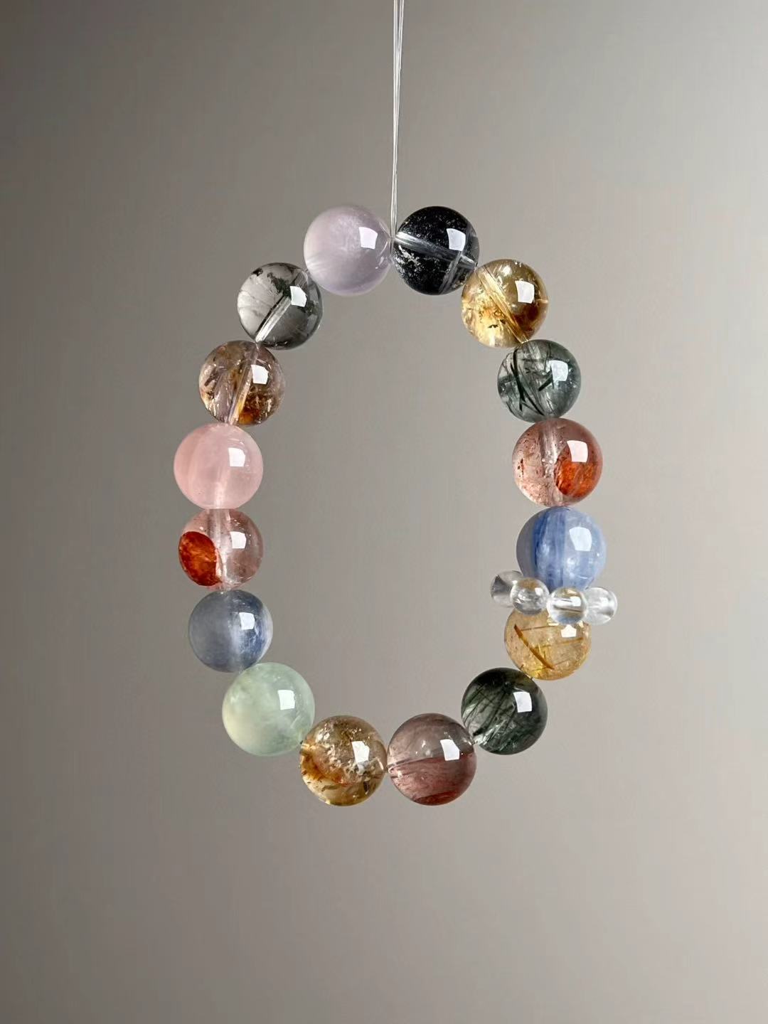 Side angle — golden rutile quartz spheres beside blue kyanite and rose quartz; clear quartz halo spacer visible.