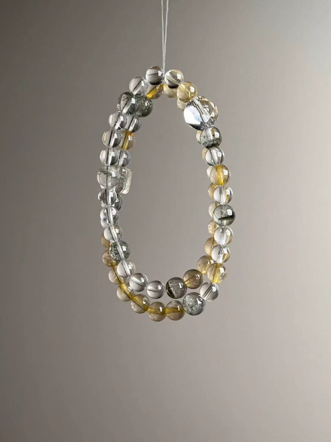 Angle view — slim strand of Golden Rutile and Clear Quartz with Green Phantom accents.