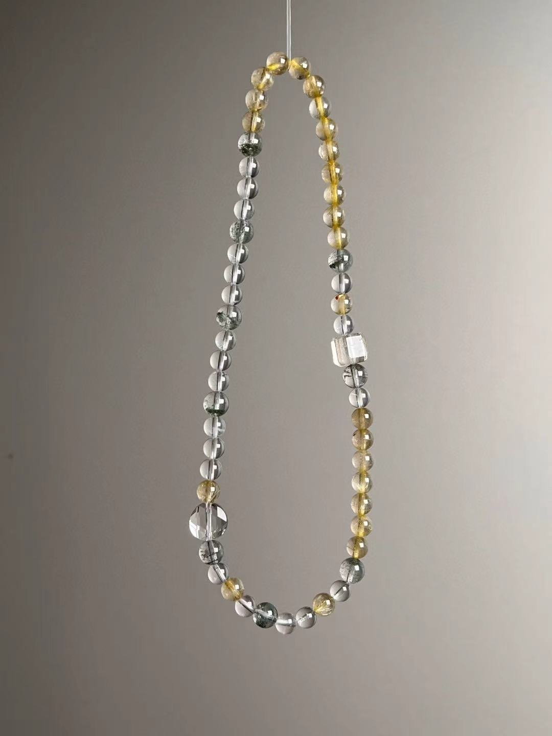 Detail layout — Clear Quartz cube accent with Golden Rutile and Green Phantom rounds.