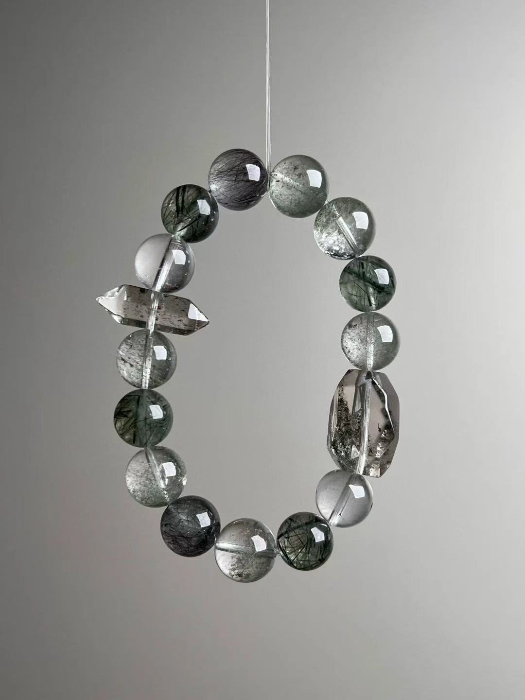 Angled view—round Green Phantom and dark rutilated beads with clear quartz contrast, ≈12.5 mm