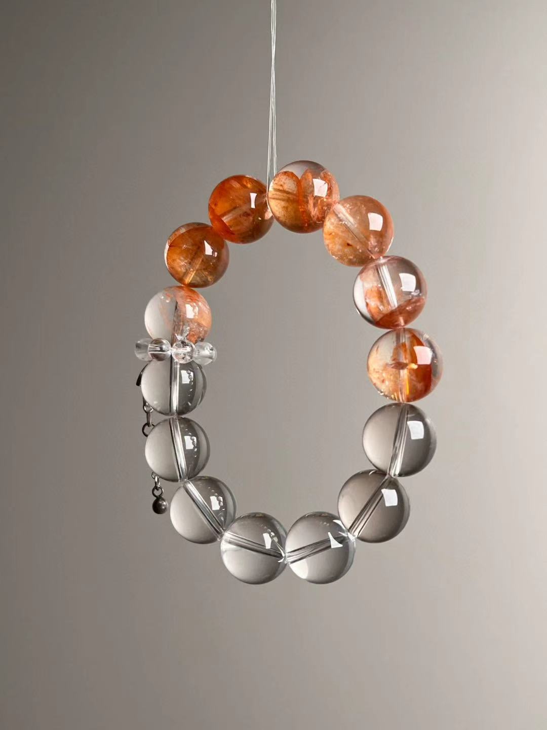 Angled hero view showing orange inclusions in Fanta Garden Quartz and the smooth Clear Quartz section, approx. 11–12 mm