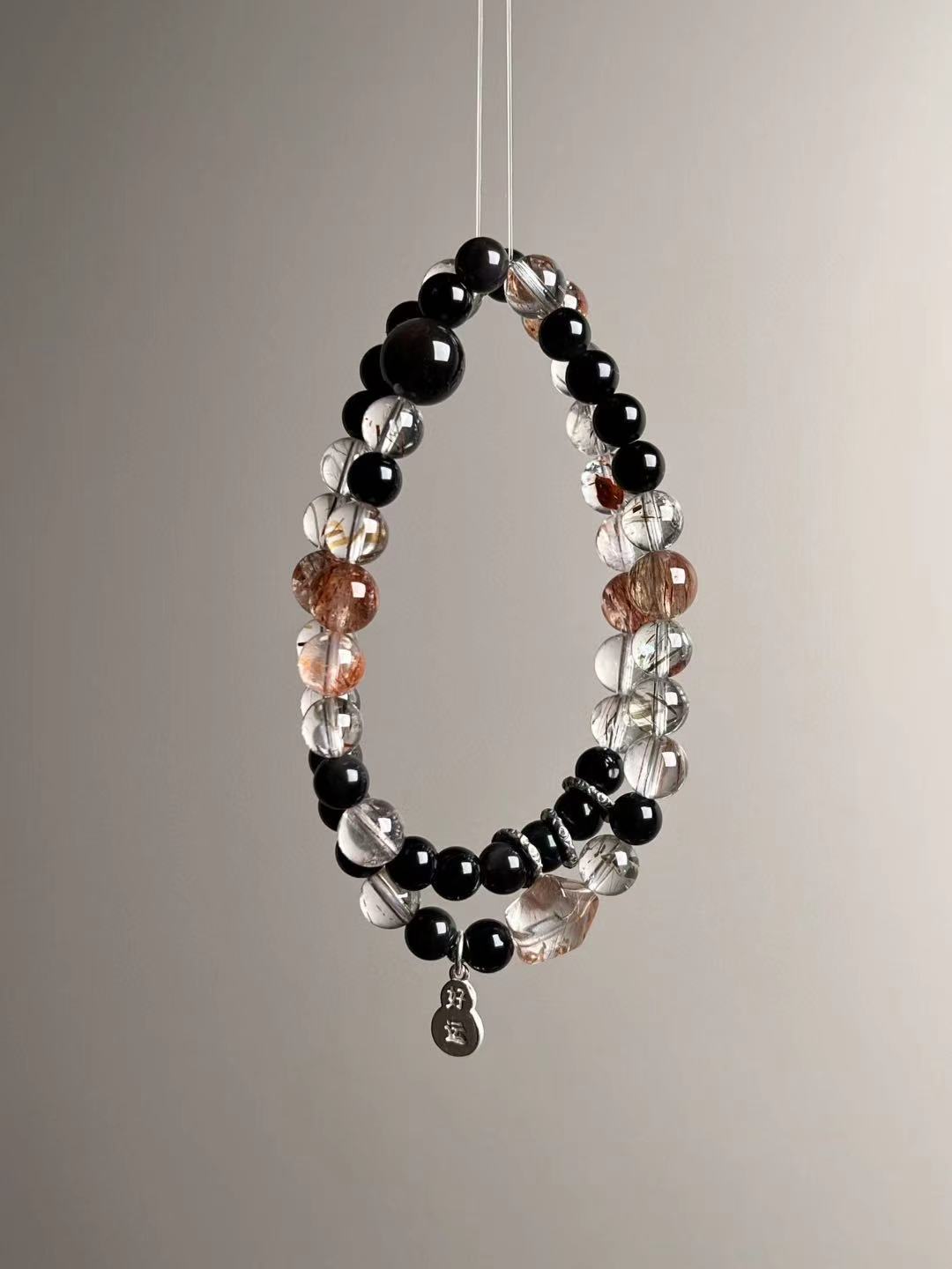 Suspended loop view highlighting golden/black inclusions of Super Seven, glossy obsidian rounds and bright sterling accents.