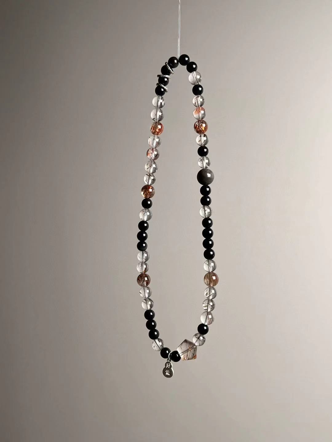 Angle shot showing the sterling lucky gourd charm and the fish runner bead among Super Seven quartz and obsidian.
