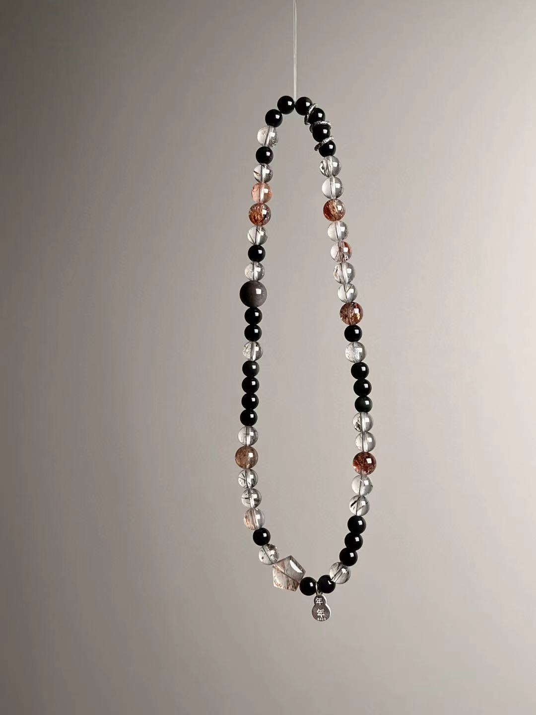 Three-quarter view emphasizing warm rutile-like threads within Super Seven and the polished obsidian contrast.