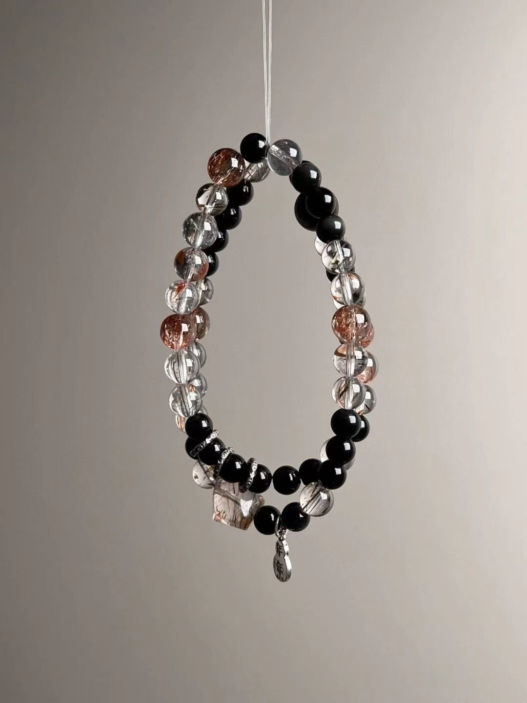 Opposite side showing geometric Super Seven cube bead and dangling sterling charm near the clasp area.