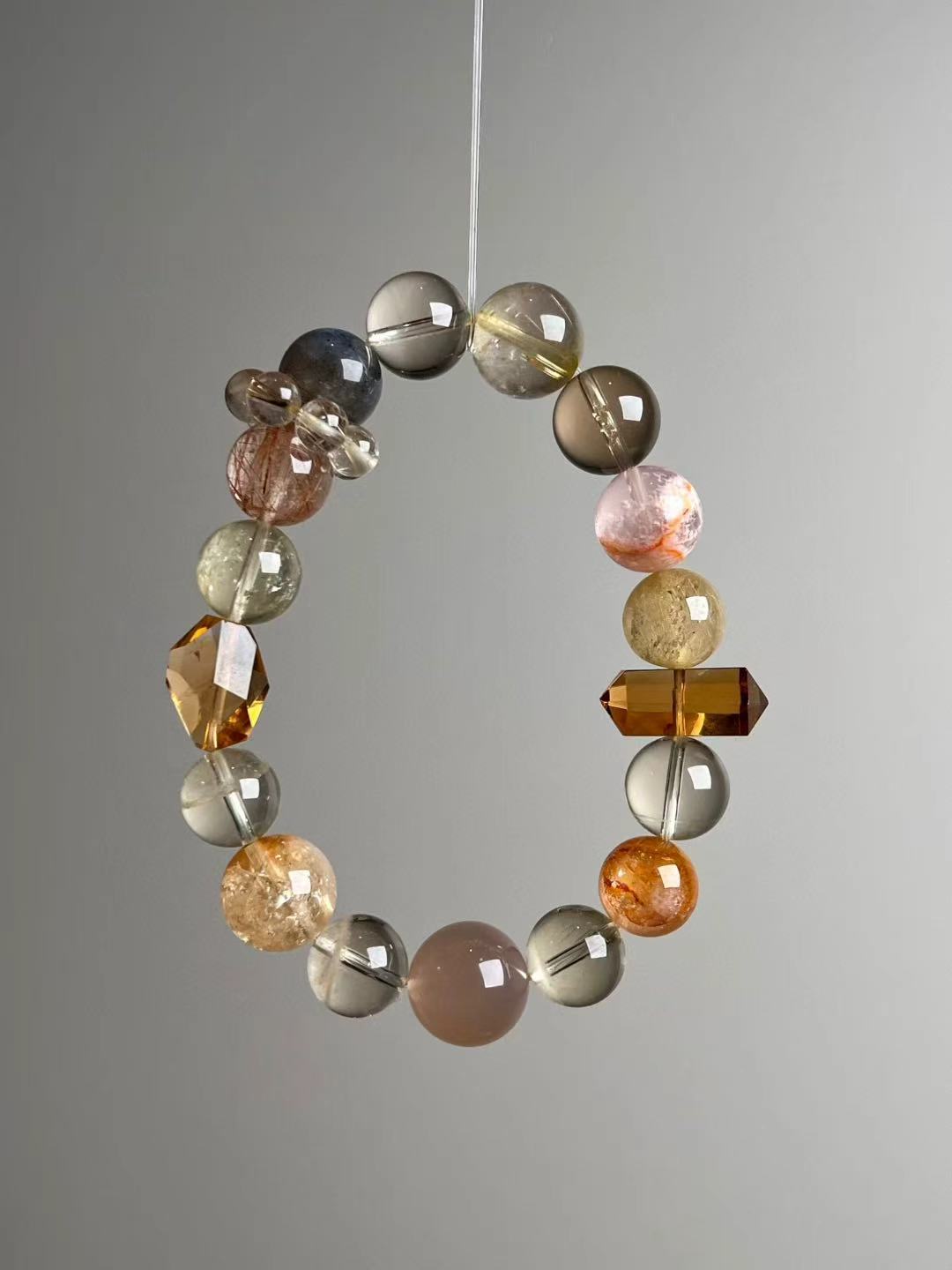 Suspended loop showing rutilated quartz, citrine rounds, gray moonstone, orange moonstone phantom and a Zambian citrine double-terminated point.