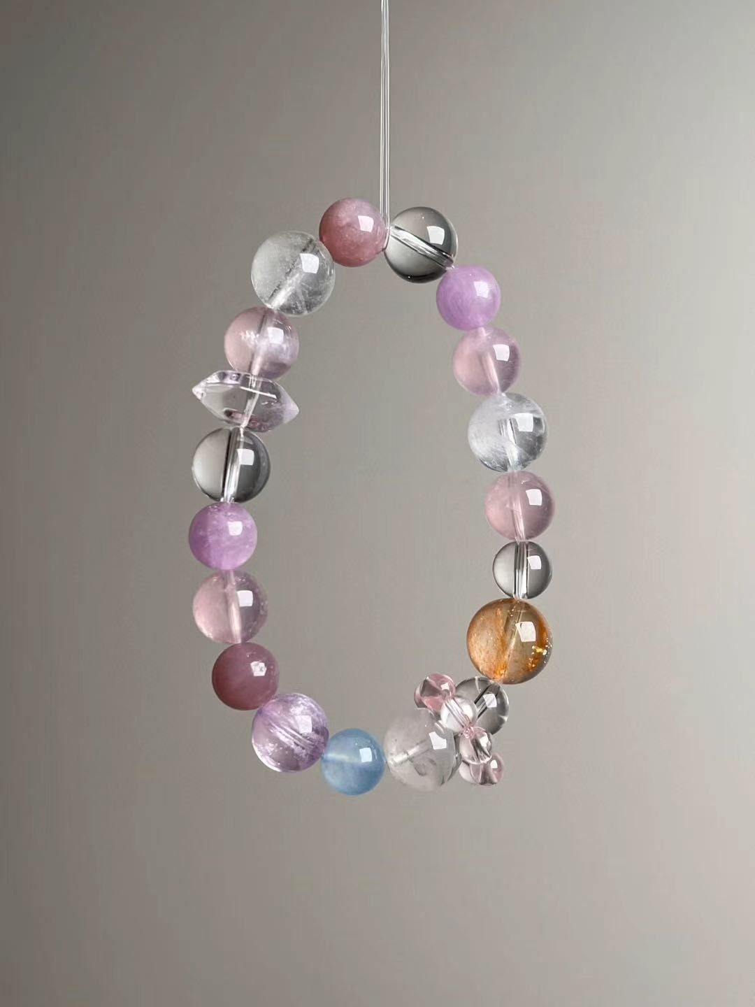 Angled hero view showing pink rose quartz, lilac lepidolite, white azeztulite and clear quartz beads with pink bead-cluster spacer