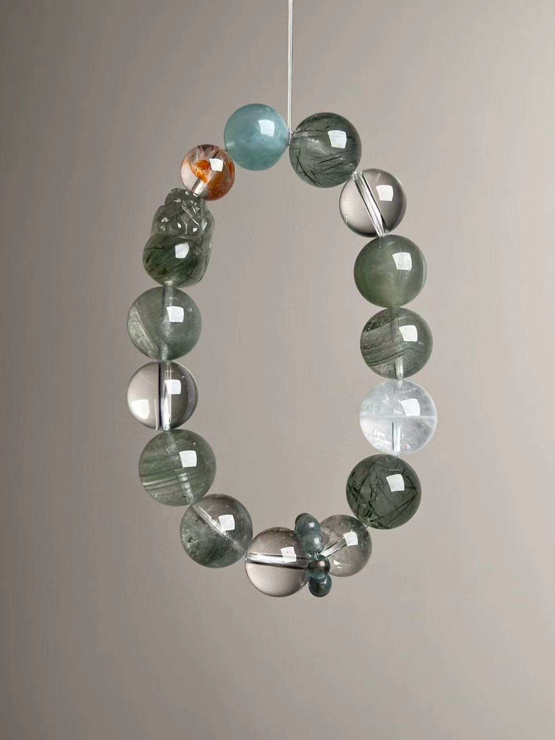 Angled hero—Green Rutilated Quartz beads with carved Pixiu, Aquamarine, Clear Quartz and phantoms; teal Apatite runner ring visible