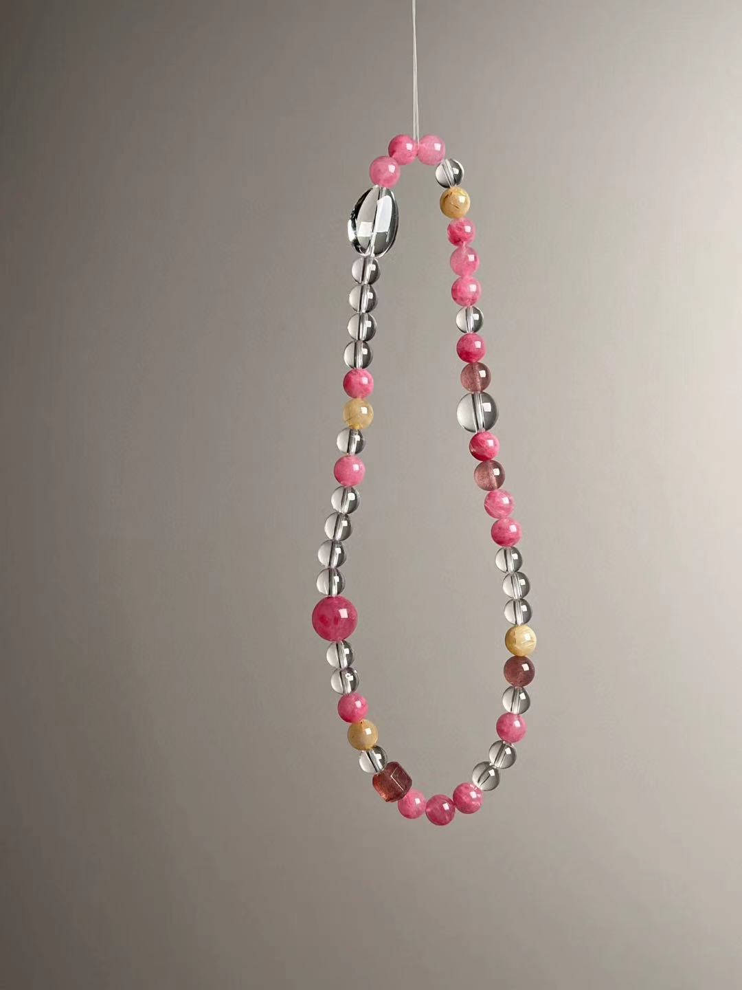 Angled hero view showing Rose Quartz, Strawberry Quartz, Golden Rutilated Quartz and Clear Quartz oval focal bead.