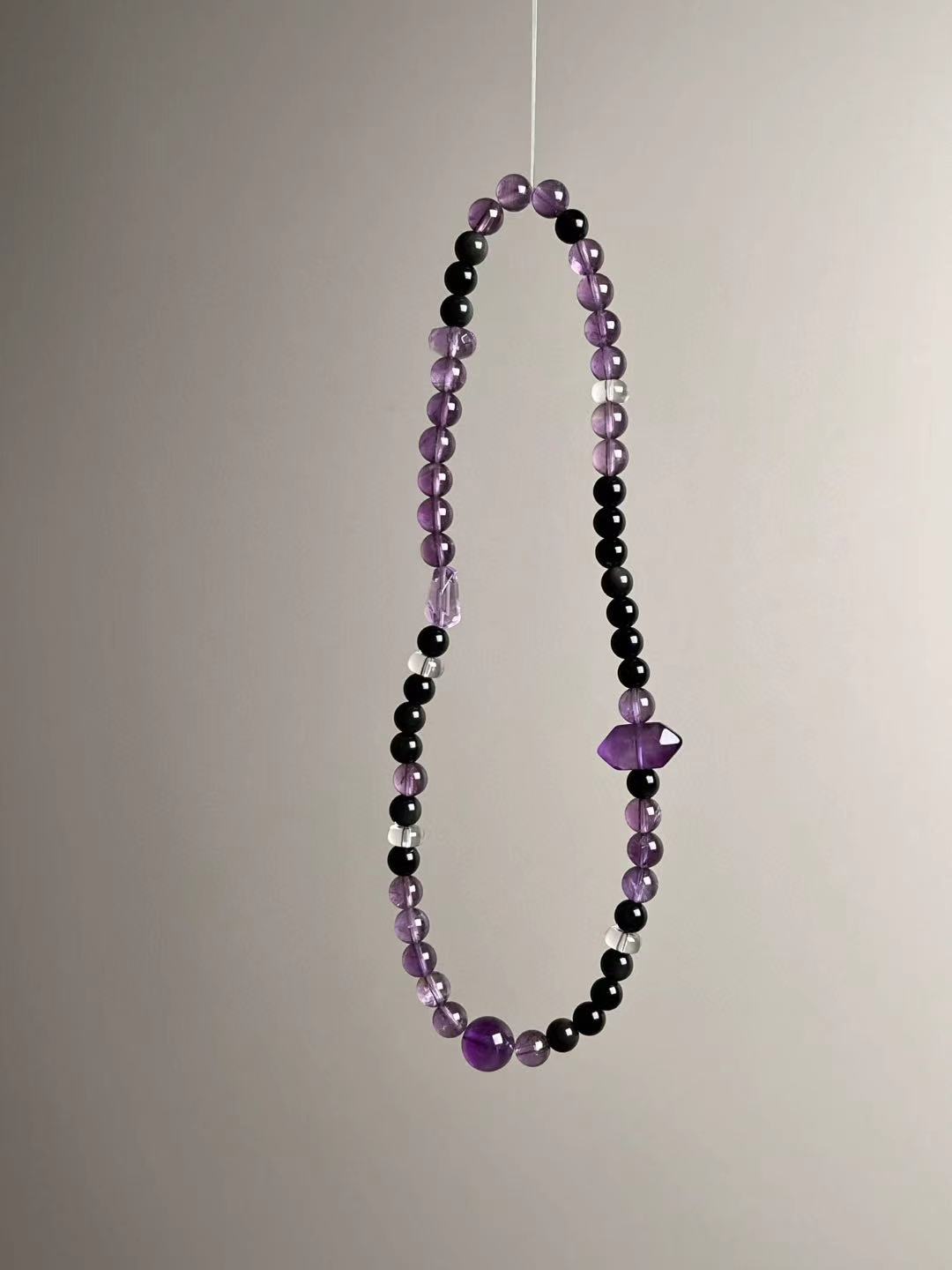 Opposite-side view featuring the second amethyst focal chip and glossy black obsidian for contrast.