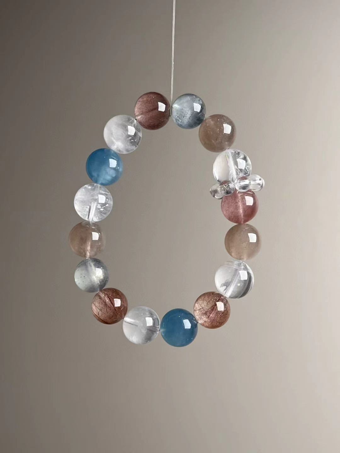 Statement crystal bracelet showing blue-flash aquamarine and red/gray rutilated quartz—angled view