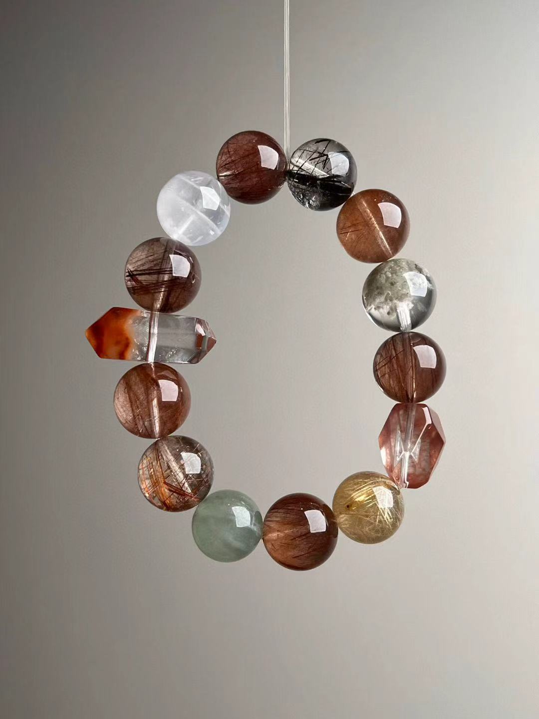 Detail of mixed hair quartz and phantom quartz beads in warm earth tones on luxury stretch bracelet