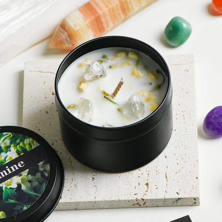 Open tin candle top view showing clear quartz chips and botanical petals set in creamy soy wax.
