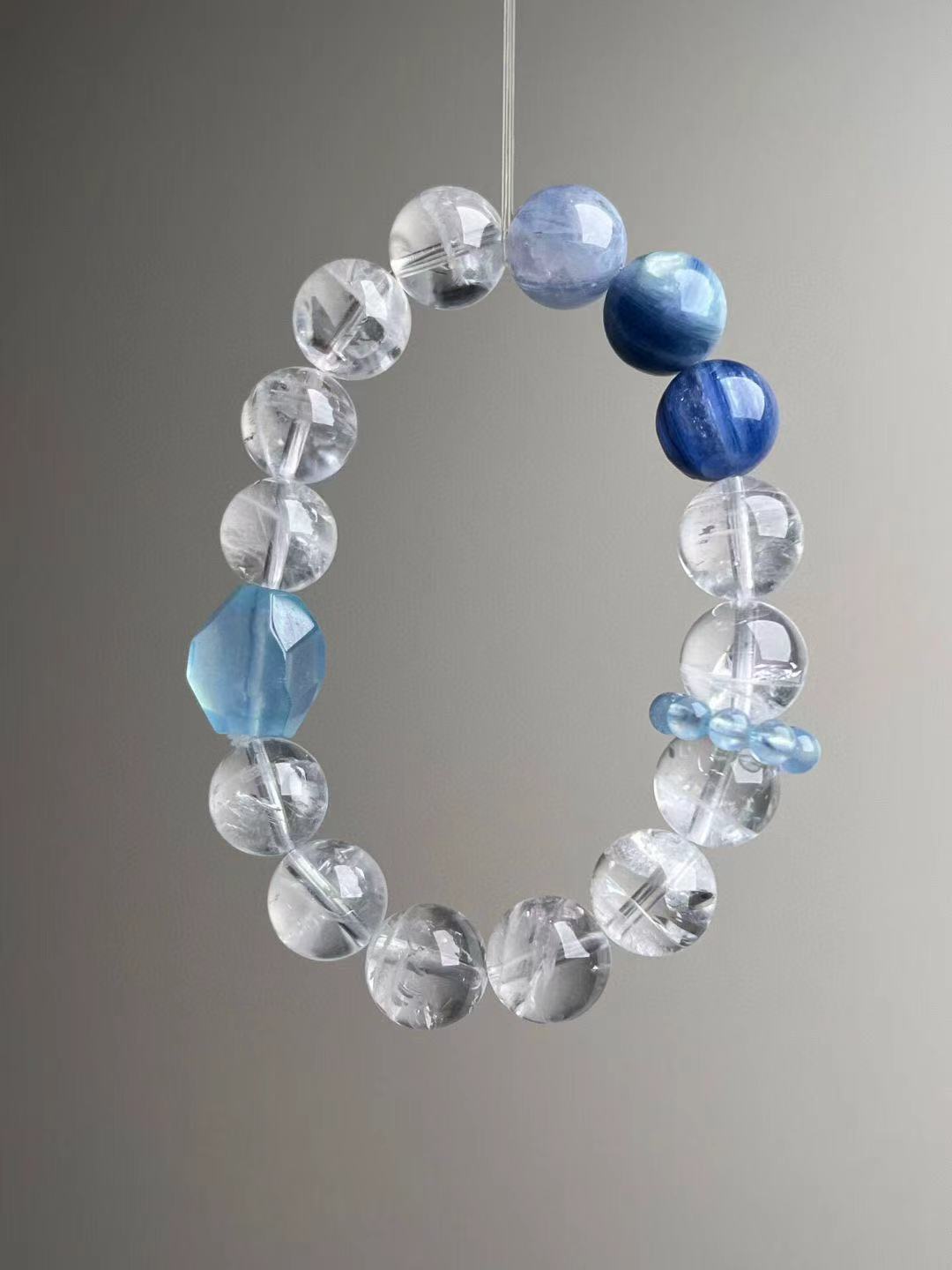 Suspended loop view highlighting white phantom quartz spheres, deep-blue kyanite and icy aquamarine accent; approx. 12 mm.