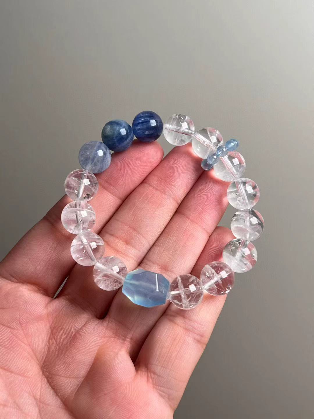 Hand shot of the Ocean Sanctuary bracelet—white phantom quartz, kyanite and aquamarine runner beads, ~12 mm rounds with ice-clear clarity.