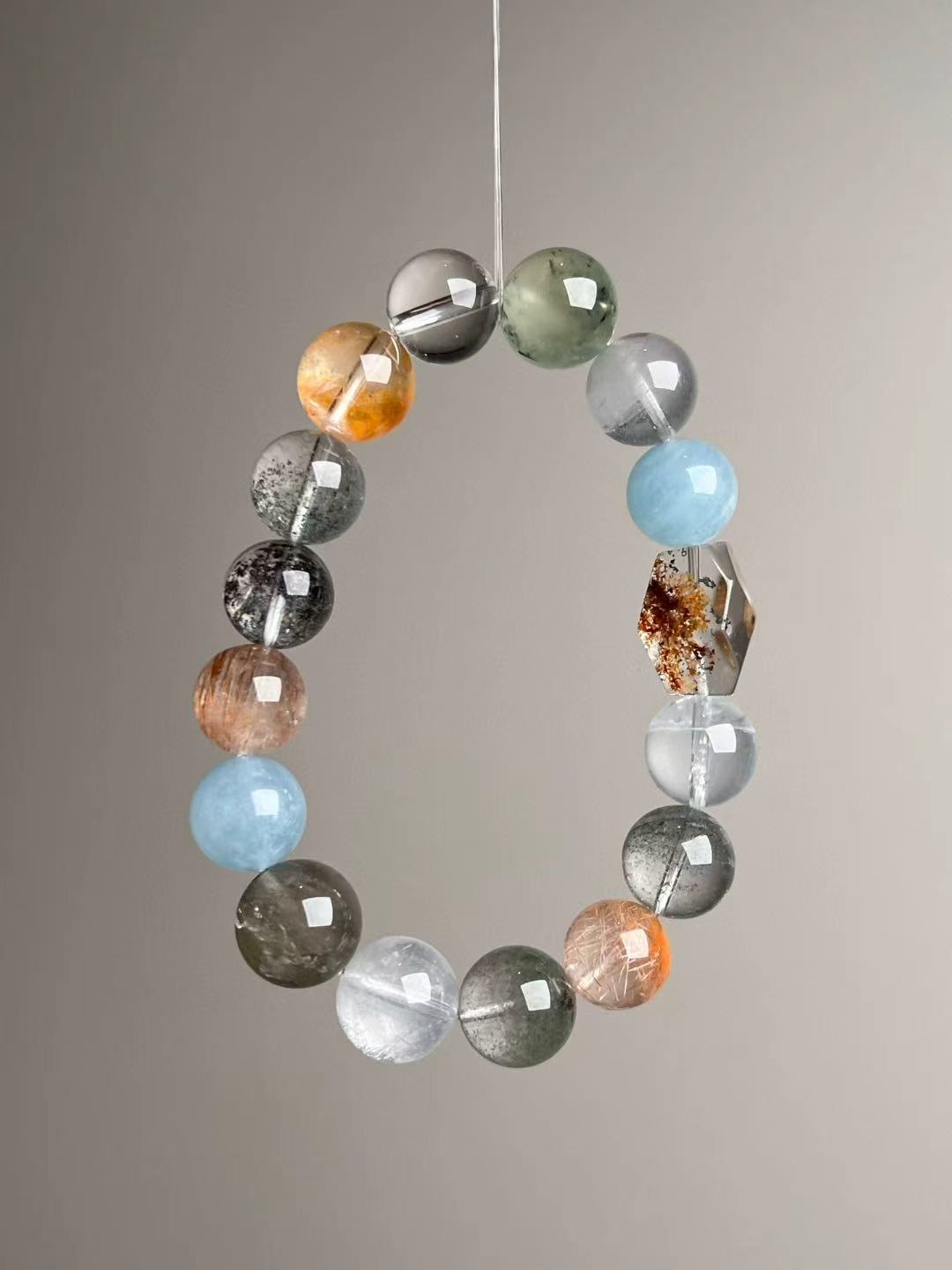 Mixed gemstone bracelet featuring golden rutile, citrine, gray moonstone, copper rutile and clear quartz, tapered 14–11 mm.