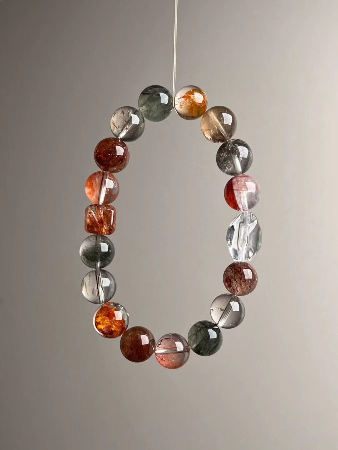 Close suspended circle capturing high-clarity segments and copper-red lepidocrocite beads; 10–11 mm polished rounds.