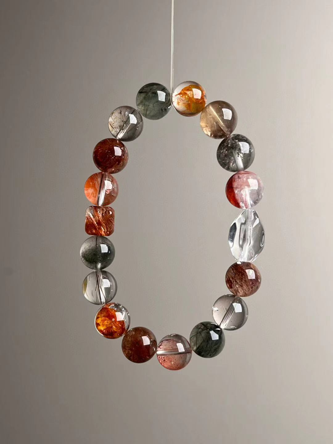 Detail of gradient from clear quartz amplifier to green phantom wealth stones; premium elastic stringing.