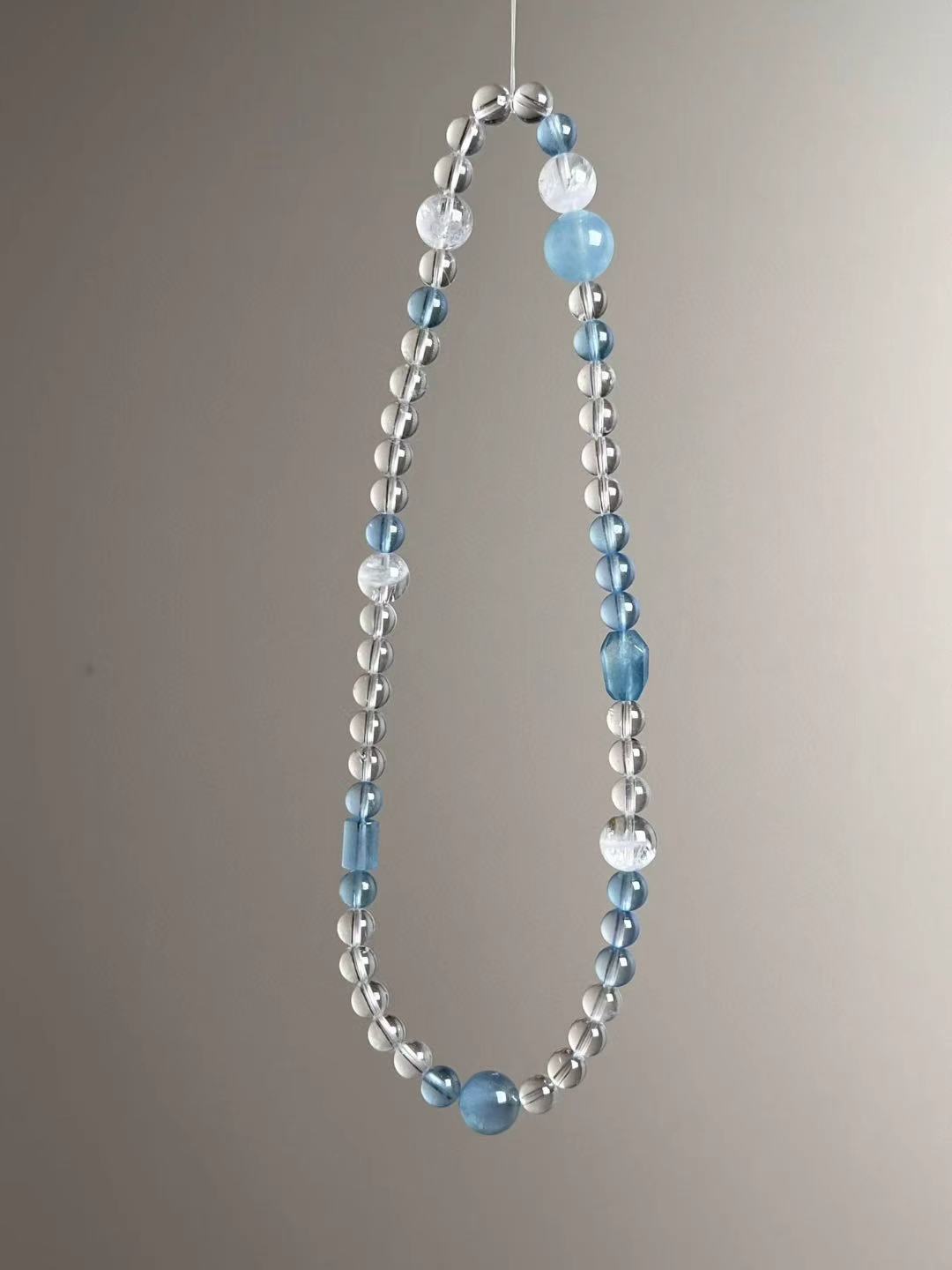 Angle view — aquamarine rounds and barrel accents with clear quartz micro rounds.