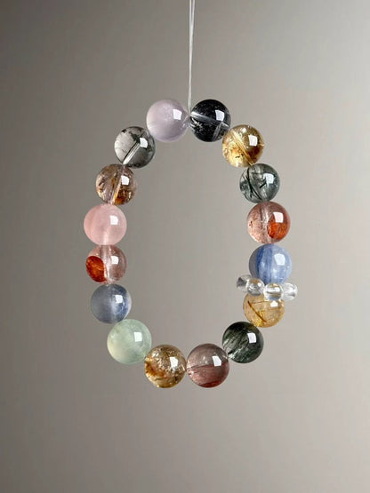Side angle — golden rutile quartz spheres beside blue kyanite and rose quartz; clear quartz halo spacer visible.