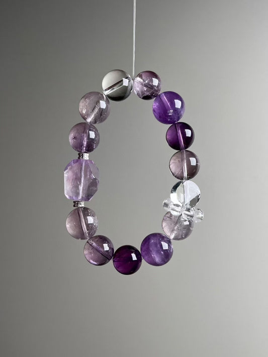 Angle view — alternating amethyst and translucent quartz rounds; purple azeztulite focal bead visible