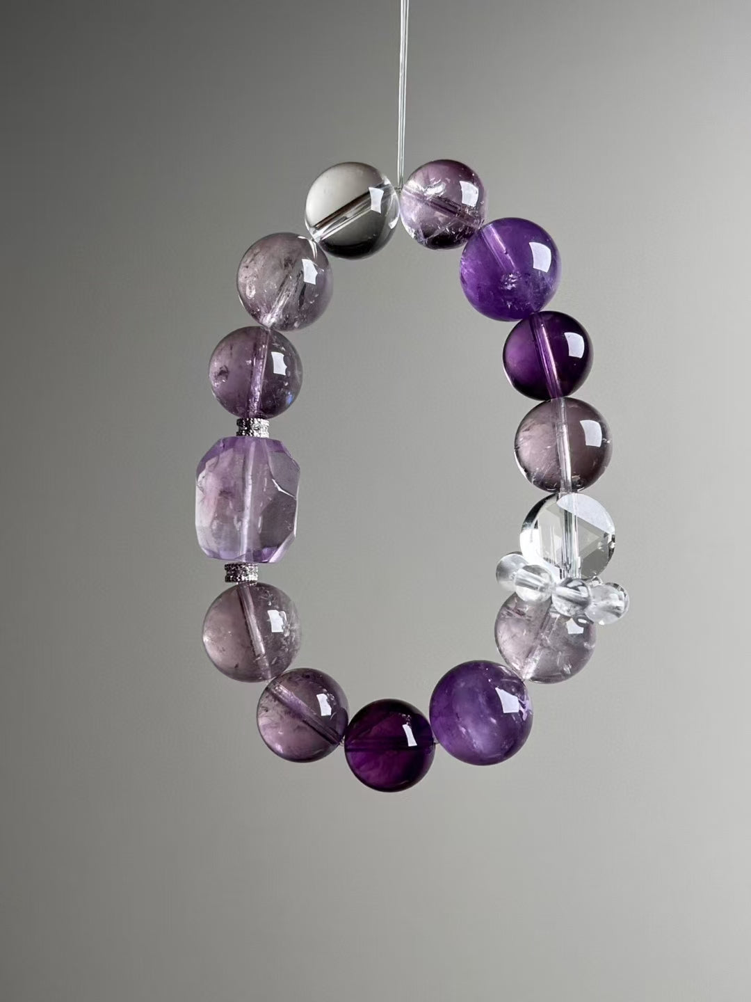 Side view — faceted Purple Azeztulite focal bead and glossy amethyst rounds; 13.6–12 mm sizing.