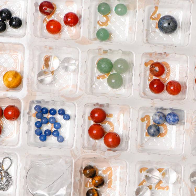 Close-up of the inner tray with assorted natural round beads in multiple sizes and colors; 24 mini compartments.