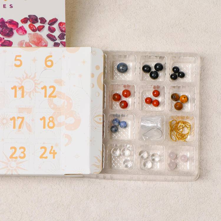Half-open advent-style box showing numbered doors and the bead tray with tools and findings.
