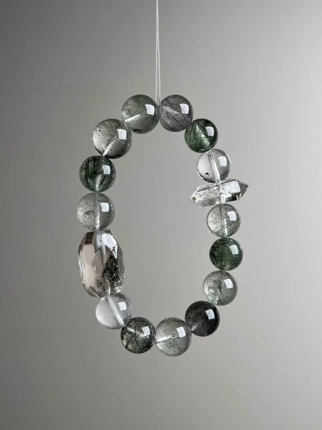Angled hero—mix of green phantom, black rutile needles, and a clean double-terminated quartz spacer