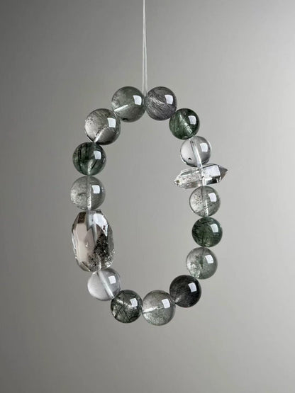 Angled hero—mix of green phantom, black rutile needles, and a clean double-terminated quartz spacer