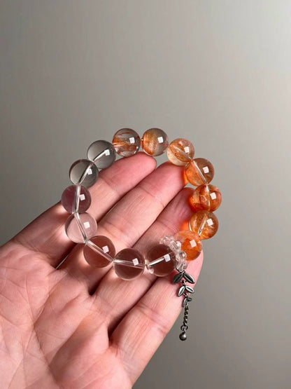 On-hand photo—bracelet mixing Fanta Garden Quartz (orange lodolite) and Clear Quartz with a bead-cluster runner and leaf charm, approx. 11–12 mm