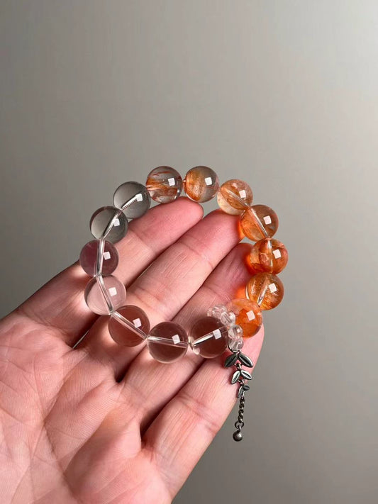 On-hand photo—bracelet mixing Fanta Garden Quartz (orange lodolite) and Clear Quartz with a bead-cluster runner and leaf charm, approx. 11–12 mm
