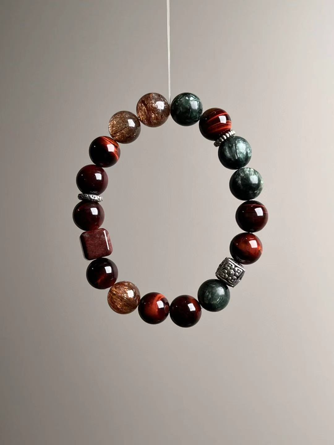 Angle shot showing the balance of red tiger’s eye, feathery seraphinite and sparkling phantom quartz accents.