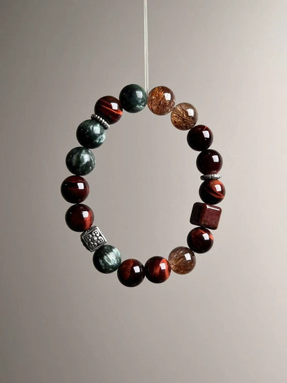 Side view focusing on black-gold Super Seven beads with golden needles beside glossy red tiger’s eye.