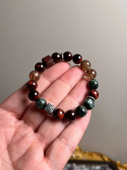 Hand shot of Crimson Accelerator bracelet — red tiger’s eye, black-gold Super Seven, seraphinite (green dragonstone) and phantom quartz, ~10.5 mm.