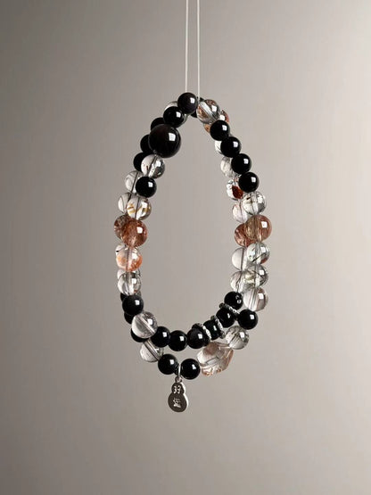 Suspended loop view highlighting golden/black inclusions of Super Seven, glossy obsidian rounds and bright sterling accents.