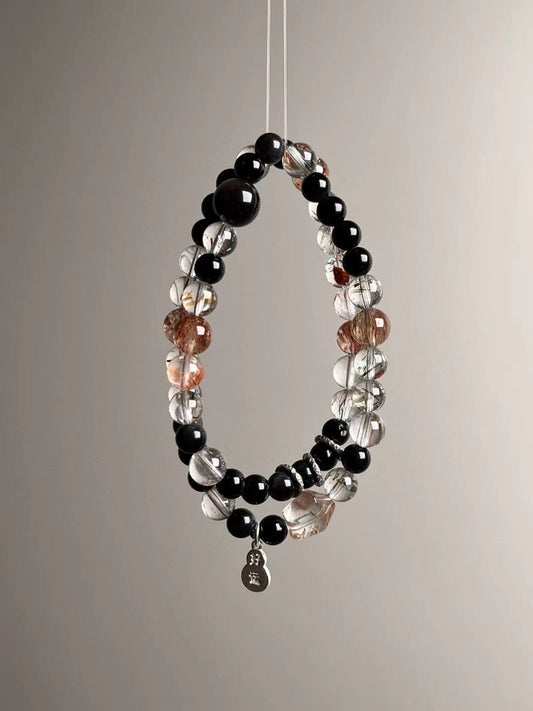 Suspended loop view highlighting golden/black inclusions of Super Seven, glossy obsidian rounds and bright sterling accents.