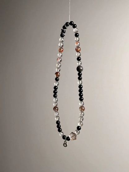 Angle shot showing the sterling lucky gourd charm and the fish runner bead among Super Seven quartz and obsidian.