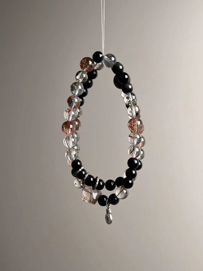 Opposite side showing geometric Super Seven cube bead and dangling sterling charm near the clasp area.