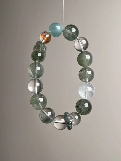 Angled hero—Green Rutilated Quartz beads with carved Pixiu, Aquamarine, Clear Quartz and phantoms; teal Apatite runner ring visible