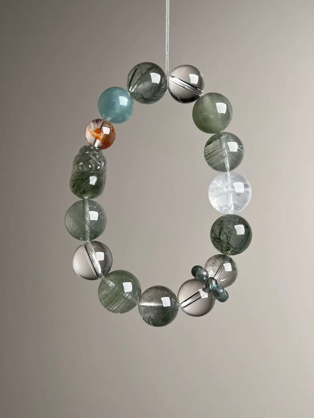 Angled hero—carved Green Rutilated Quartz Pixiu beside a bright orange Fanta bead-cluster accent and Aquamarine bead