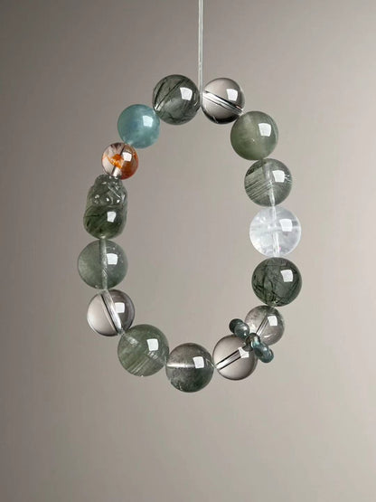 Angled hero—carved Green Rutilated Quartz Pixiu beside a bright orange Fanta bead-cluster accent and Aquamarine bead