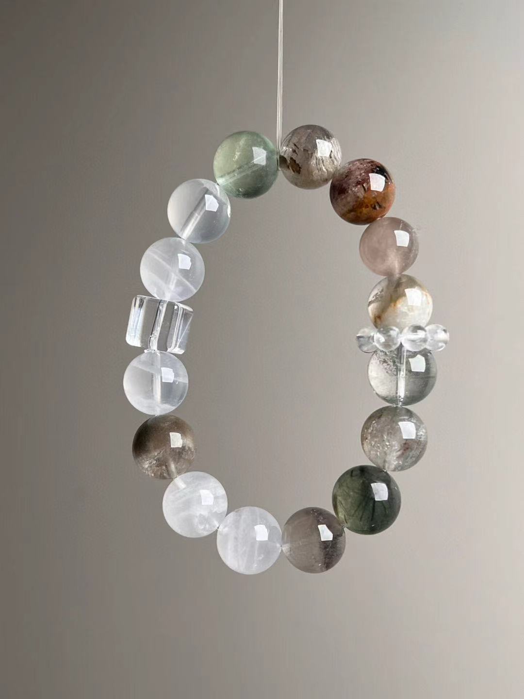 Close suspended loop emphasizing layered phantom structures; clear-quartz runner ring visible.