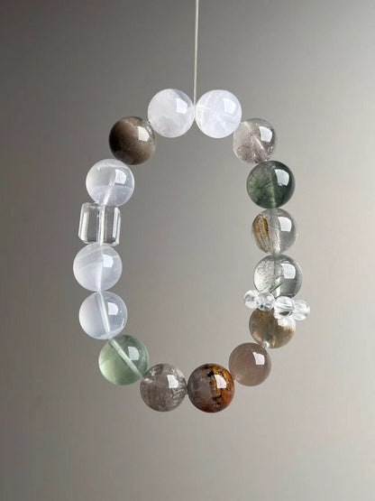 Suspended loop showing icy clarity and balance; clear-quartz cube focal with white/mossy inclusions.