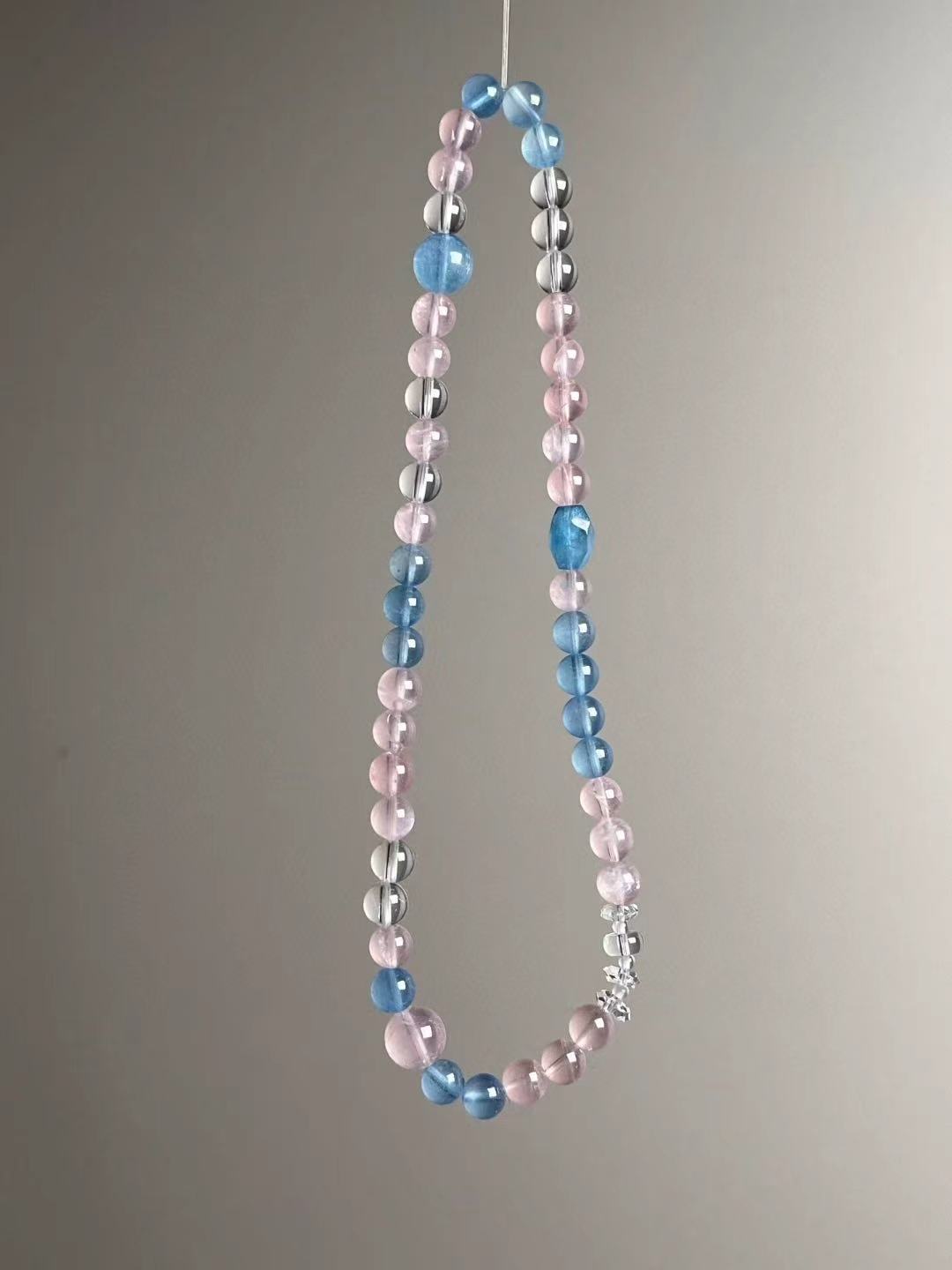 Suspended loop view showing alternating rose quartz and aquamarine rounds with clear-quartz spacers in a soft pastel palette.