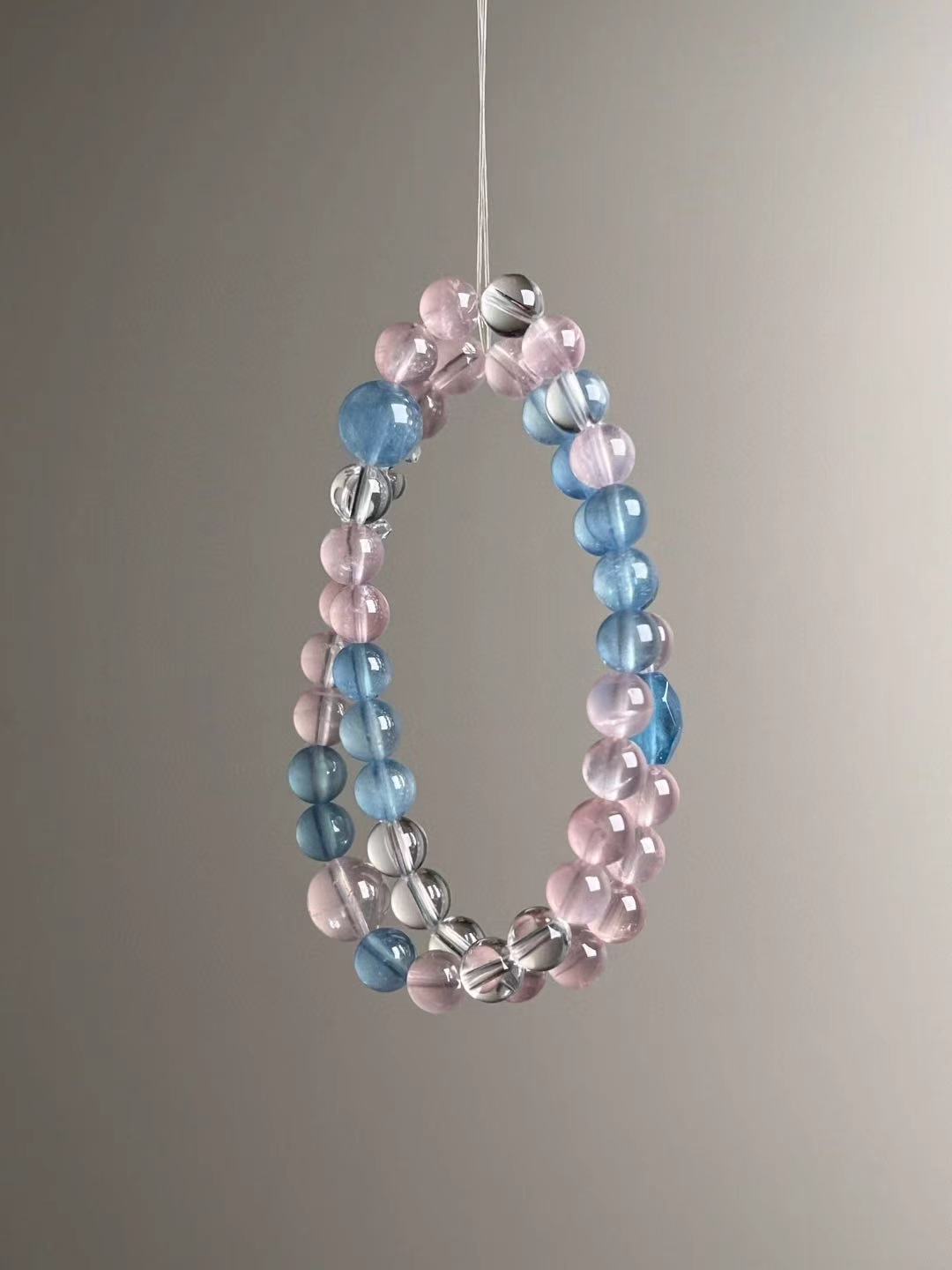 Close three-quarter view highlighting luminous aquamarine blues next to blush-pink rose quartz rounds